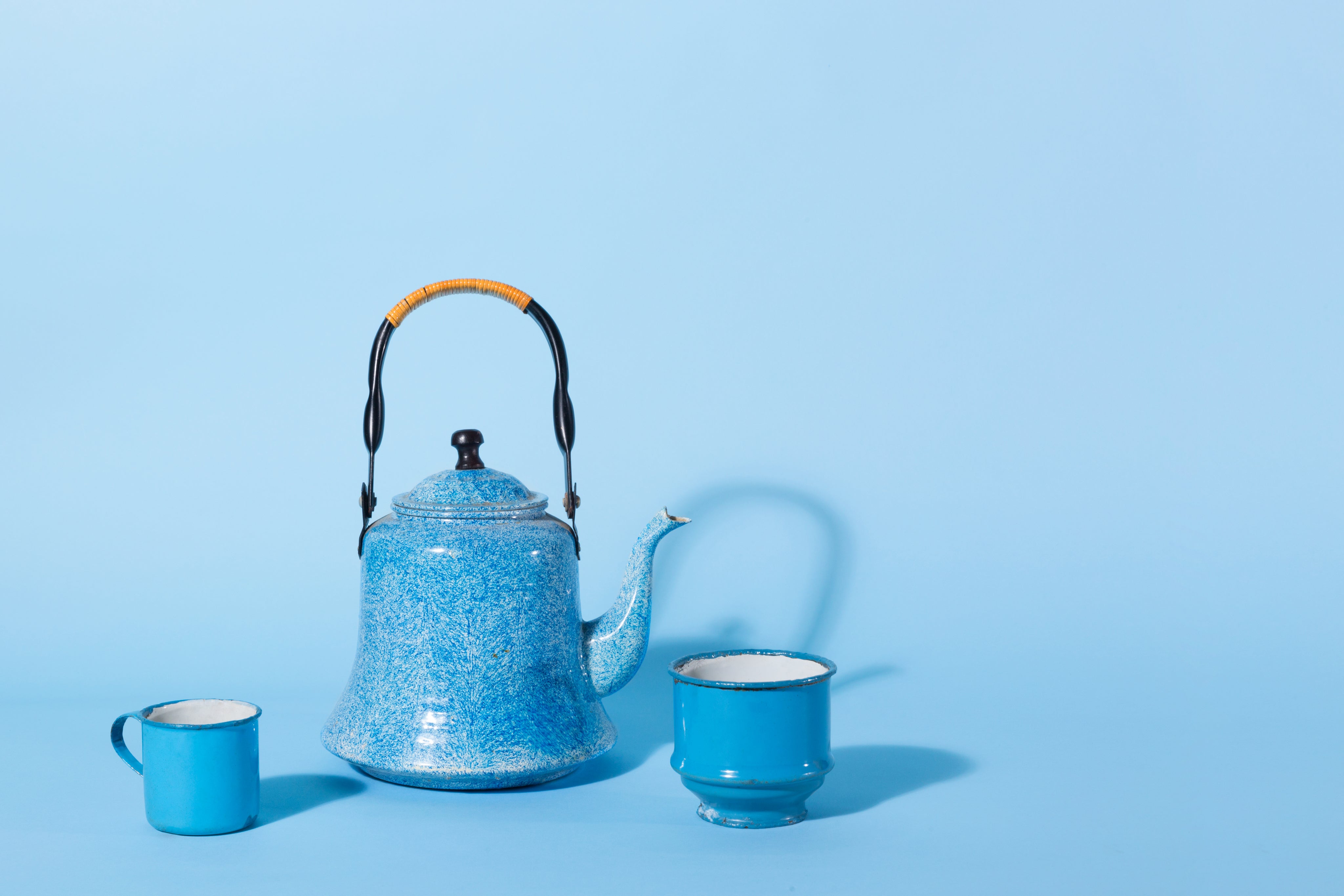 a-blue-kettle-and-tin-mug-against-a-blue-background.jpg